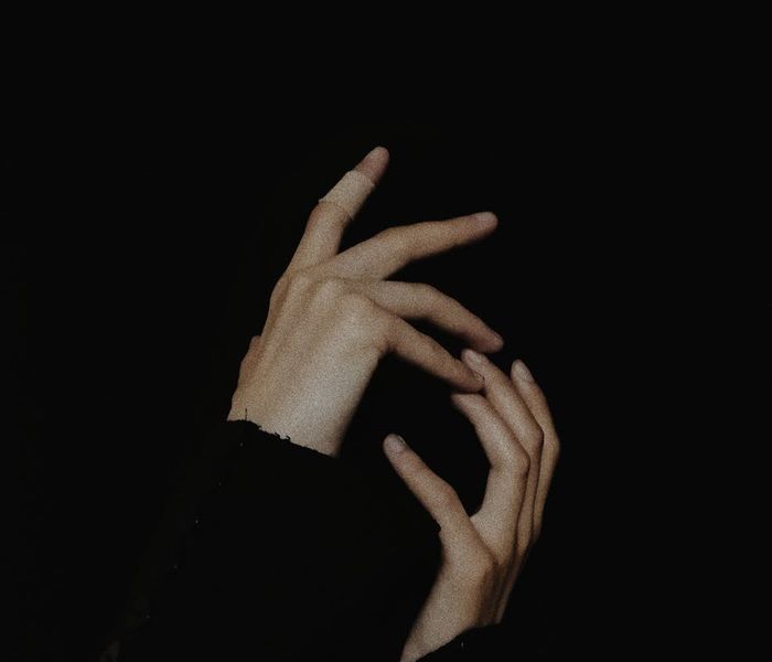 Person in a balanced pose against a dark, minimalist background with ruby accents.