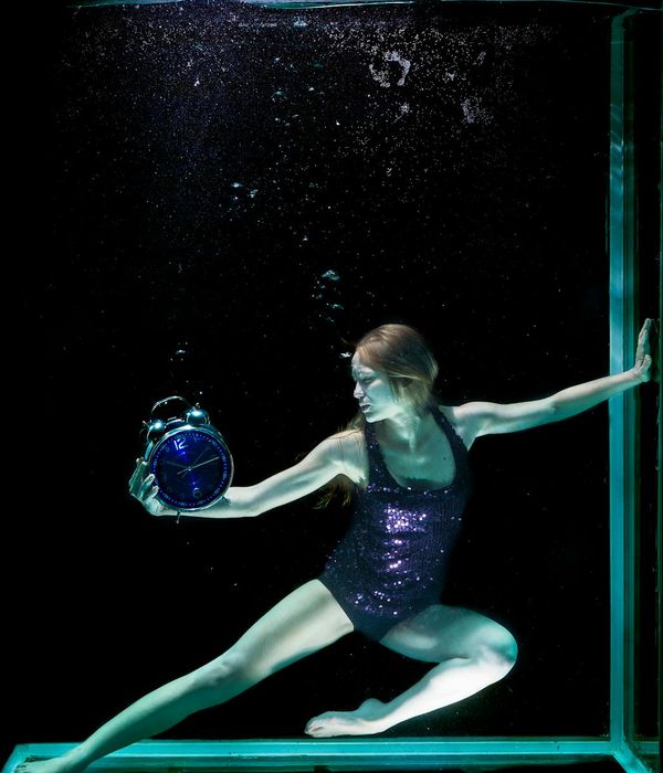 Woman performing a graceful movement in a dark studio with ruby light.